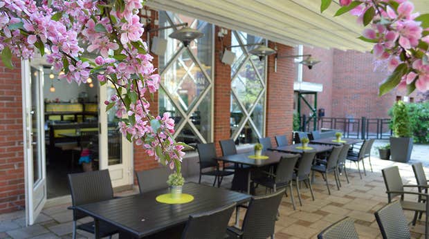 Istuinryhmiä ja kirsikkapuun kukkia Quality Hotel Galaxenin terassilla Borlängessä