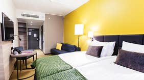 Kahden hengen Superior-huone parivuoteella, sohvalla, keltaisella seinällä ja istuinryhmällä, Quality Hotel Winn Haninge -hotellissa